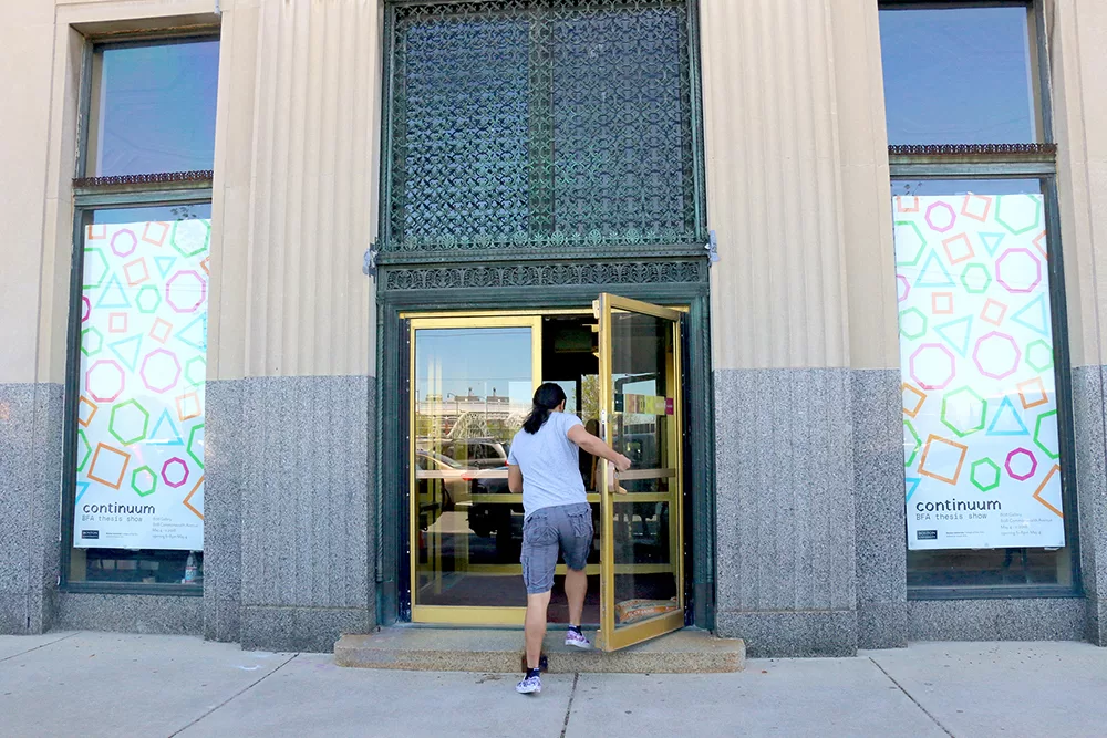 student walking into gallery with banners on either side thesis show branding